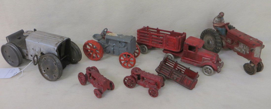 Seven tractors and trucks including Auburn rubber tract: Seven tractors and trucks including Auburn rubber tractor, 2 small 3.5" cast iron tractors (missing heads on driver), cast iron 6" tractor with orange wheels, tin windup tractor (missing grill and tre