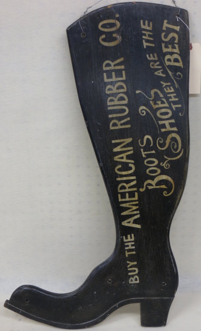 Wooden figural shoe maker's sign in the form of a boot: Wooden figural shoe maker's sign in the form of a boot entitled "BUY THE AMERICAN RUBBER CO. BOOTS & SHOES - THEY ARE THE BEST". 31.25"H - There are 5 holes in the boot, 3 along the bottom and 2 at th