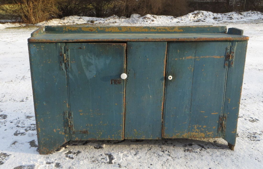 Early 2 door low cupboard - old blue paint but probably: Early 2 door low cupboard - old blue paint but probably not original - appears to be a lower section of a larger cupboard - cutout base with "M" shaped cutouts on sides - 18th century. 54.5"W x 15.25"
