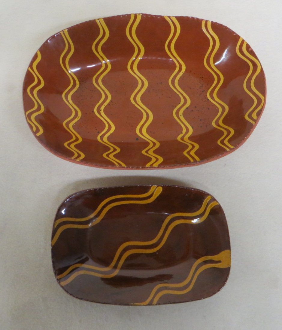 Two Redware loaf dishes with yellow slip decorations: Two Redware loaf dishes with yellow slip decorations and crimped edges signed the smaller signed L. Breinninger 1984 "Sunny Day" 6.5" x 9.5" and L. Breininger Nov. 28, 1987 "Rainy Day" - 9.5" x 14".