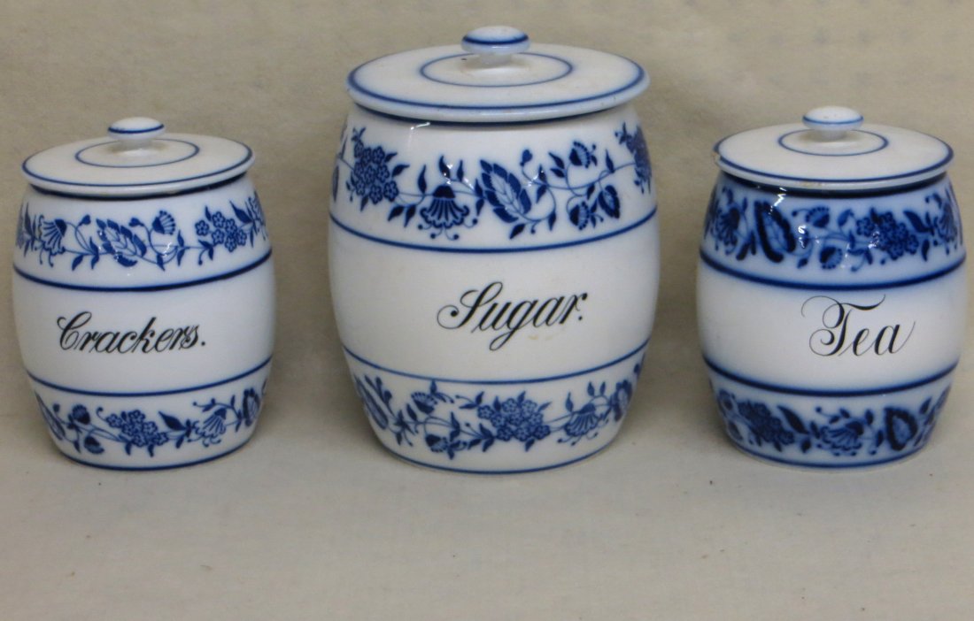 Three German blue and white canisters in the blue onion: Three German blue and white canisters in the blue onion pattern - Sugar, Crackers and Tea - Largest being 9.5" - chips to lid of Tea canister. Late 19th century.