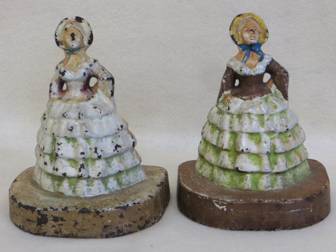 Two cast iron 19th Century women in hoop skirts: Two cast iron 19th Century women in hoop skirts doorstops both unmarked in original paint. 5.75" H X 4.5" W at base