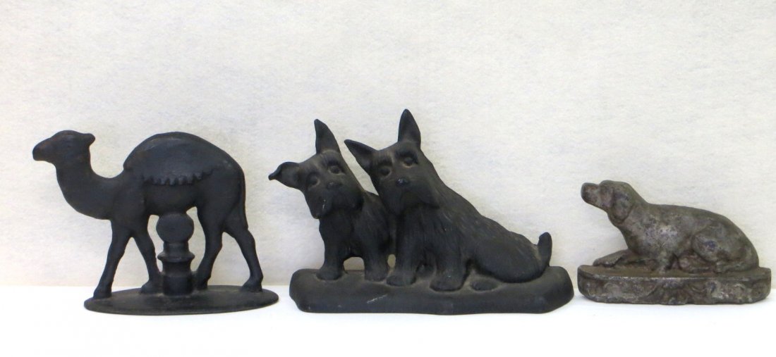 Three cast iron doorstops.: Three cast iron doorstops including a resting Retriever dog 6"W x 3 1/4" H in old paint, a pair of Scottie Dogs 9" W X 5.75" H, and a full bodied Camel in old black paint. 7.25" W X 5.5" H