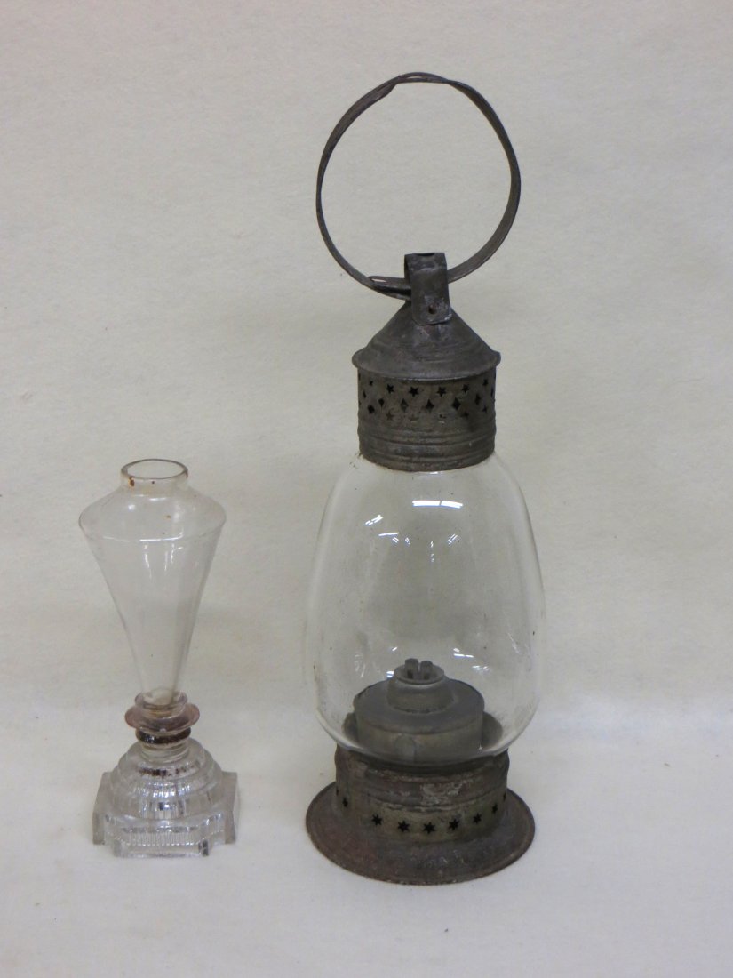 Two early lighting devices including Sandwich glass: Two early lighting devices including Sandwich glass whale oil lamp (no burner) note: .25" chip at the base of the font - 8.25"H and a pierced tin lantern with handle and glass shade - original burner 