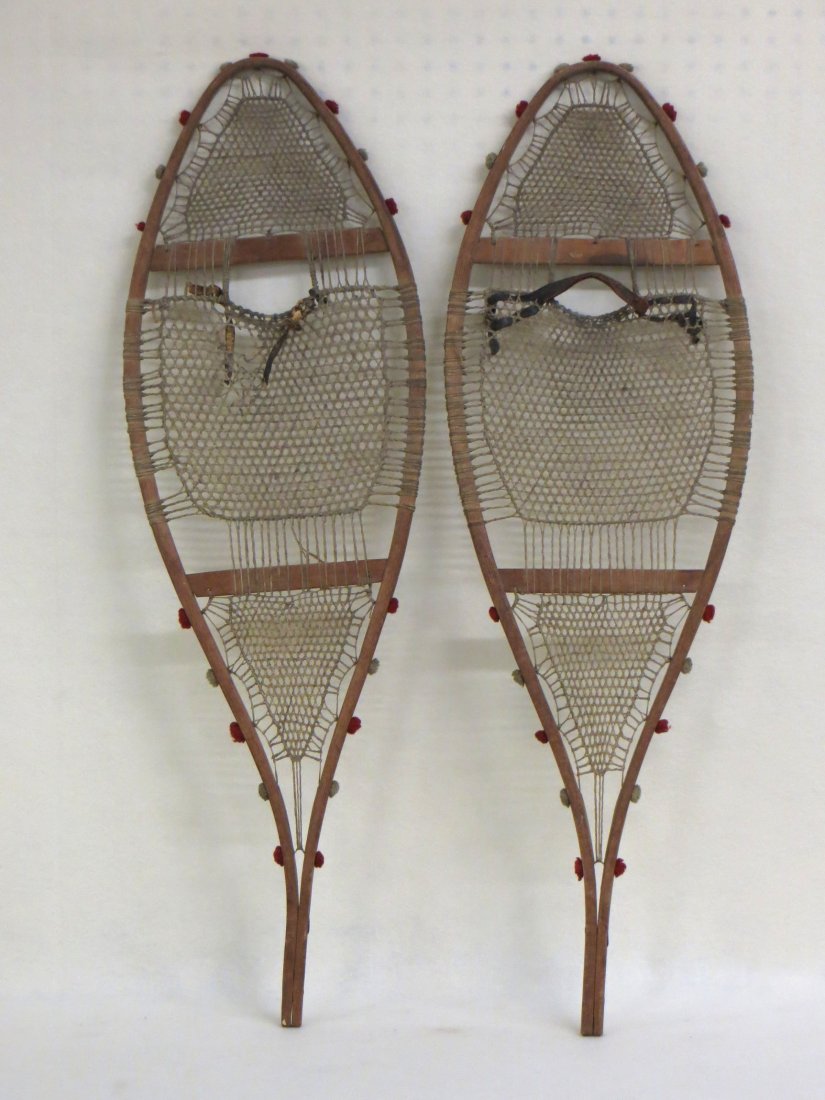 Pair of Native American snowshoes with red and white: Pair of Native American snowshoes with red and white wool threads at edges constructed of oak bentwood strung with sinew. Some minor breaks to sinew, overall good condition, size is 37"L.