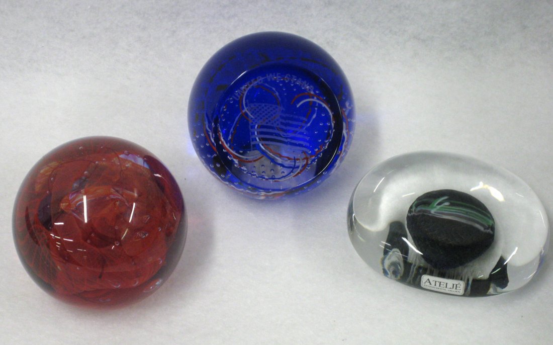 Three glass paperweights: Caithness glass "United we: Three glass paperweights: Caithness glass "United we Stand" in original box, Caithness Crucible Scotland, and Atelje designed and signed by Bertil Vallien. All in very good to excellent condition.