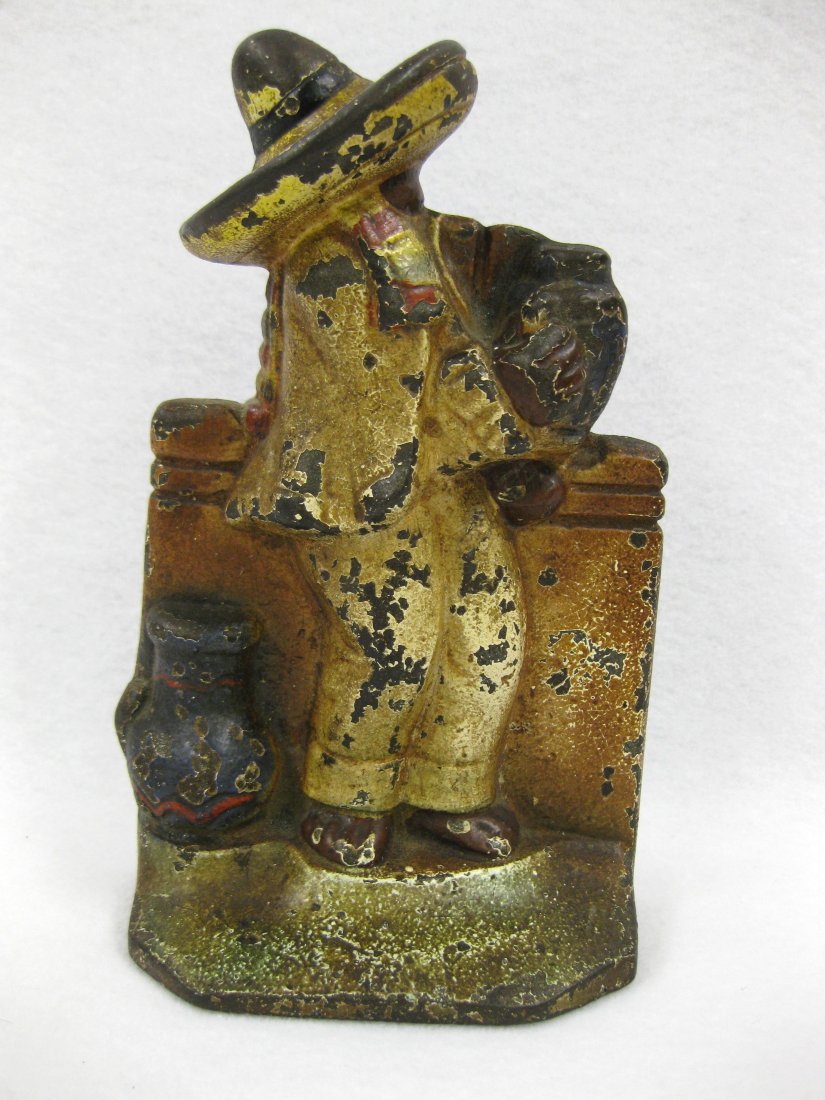 Colorful cast iron door stop of Mexican wearing: Colorful cast iron door stop of Mexican wearing sombrero holding pottery - 8"H. Good original paint with minor paint loss.