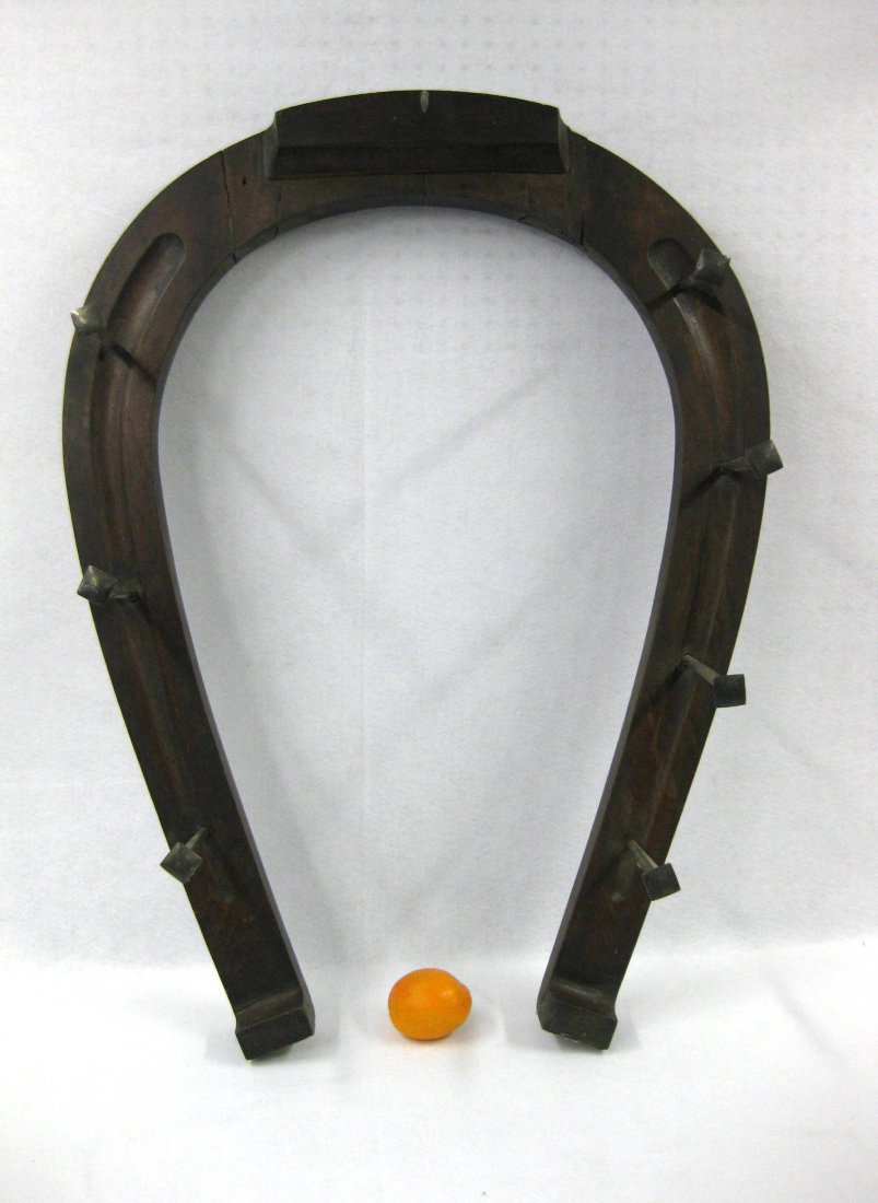 Blacksmith trade sign in the form of a large wooden: Blacksmith trade sign in the form of a large wooden horseshoe with hand made iron spikes having silver caps. Late 19th century. 29"W x 39"H. Several old crest repairs noticeable on reverse, otherwise