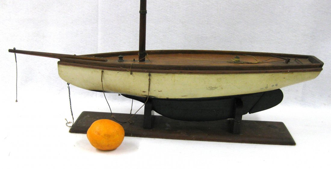 Single mast sail boat model in original paint. Probably: Single mast sail boat model in original paint. Probably late 19th century. Hull 25.5"L x 7"H to top of deck. Appears to retain original white and green paint. Working rudder. Missing sails and small s