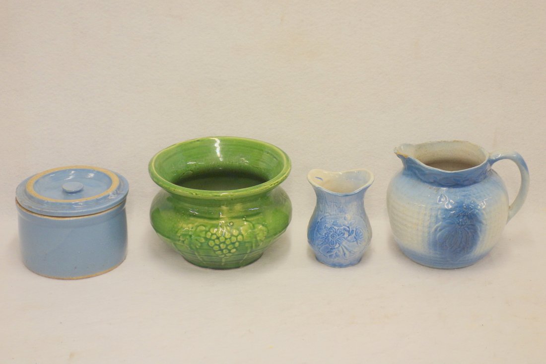 Four pieces of stoneware including an embossed blue an: Four pieces of stoneware including an embossed blue an white pitcher 6 1/2" H with chips to the spout, embossed blue and white vase, a blue covered butter crock and a green spittoon. All are in good c