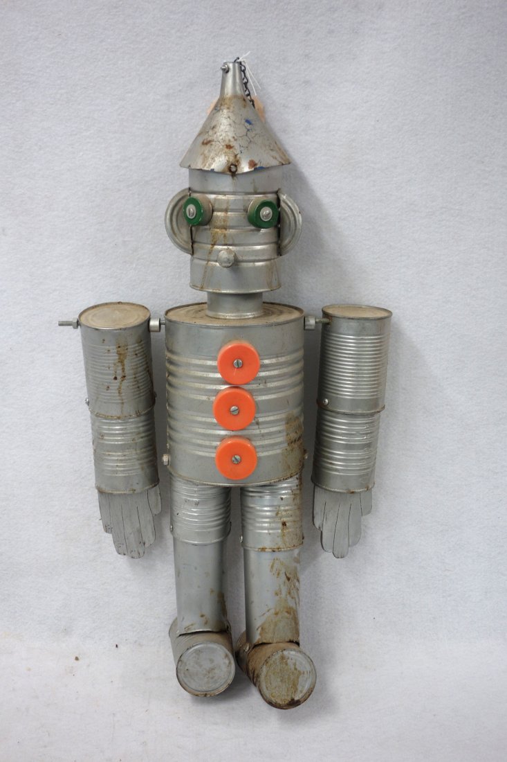 Folk art version of The Tin Man from The Wizard Of Oz: Folk art version of The Tin Man from The Wizard Of Oz made of tin cans, a funnel, bottle caps, etc.. 27"H.circa 1980's. Good condition.