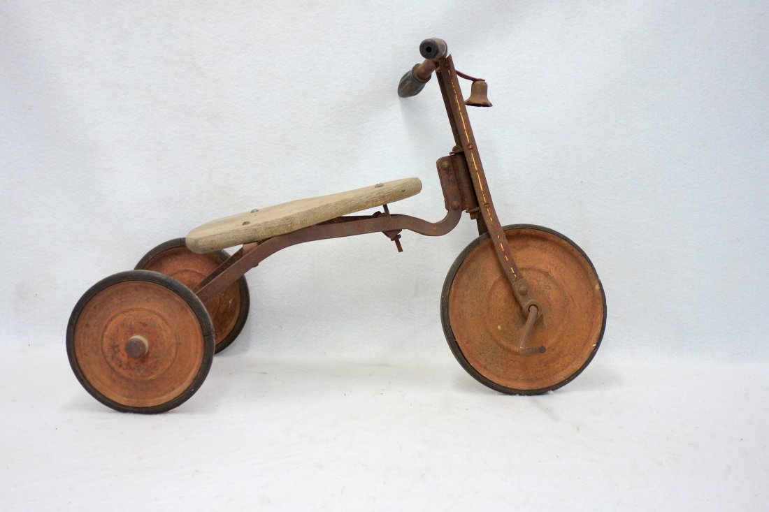 Early 20th C. tricycle with a wooden seat and hard: Early 20th C. tricycle with a wooden seat and hard rubber wheels, remnants of old red paint and white pinstripe. No pedals and front rubber wheel, some losses.