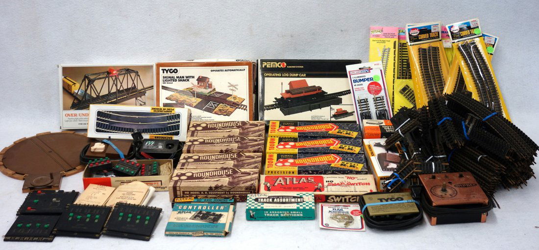 Two boxes of HO scale train parts, track, and models: Two boxes of HO scale train parts, track, and models including, Bachman blinking bridge new in the box, Penco operating log dumper new in the box, Tyco yard shack new in the box, etc. All are in good