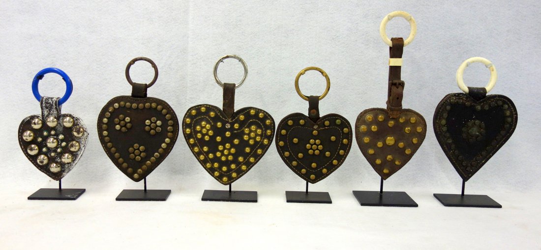 Six vintage martingale heart shaped leather pendants: Six vintage martingale heart shaped leather pendants with silver/chrome applied ornaments 5"H to 6"H - all in very good condition, circa early 20th century. All displayed on iron museum mounts.