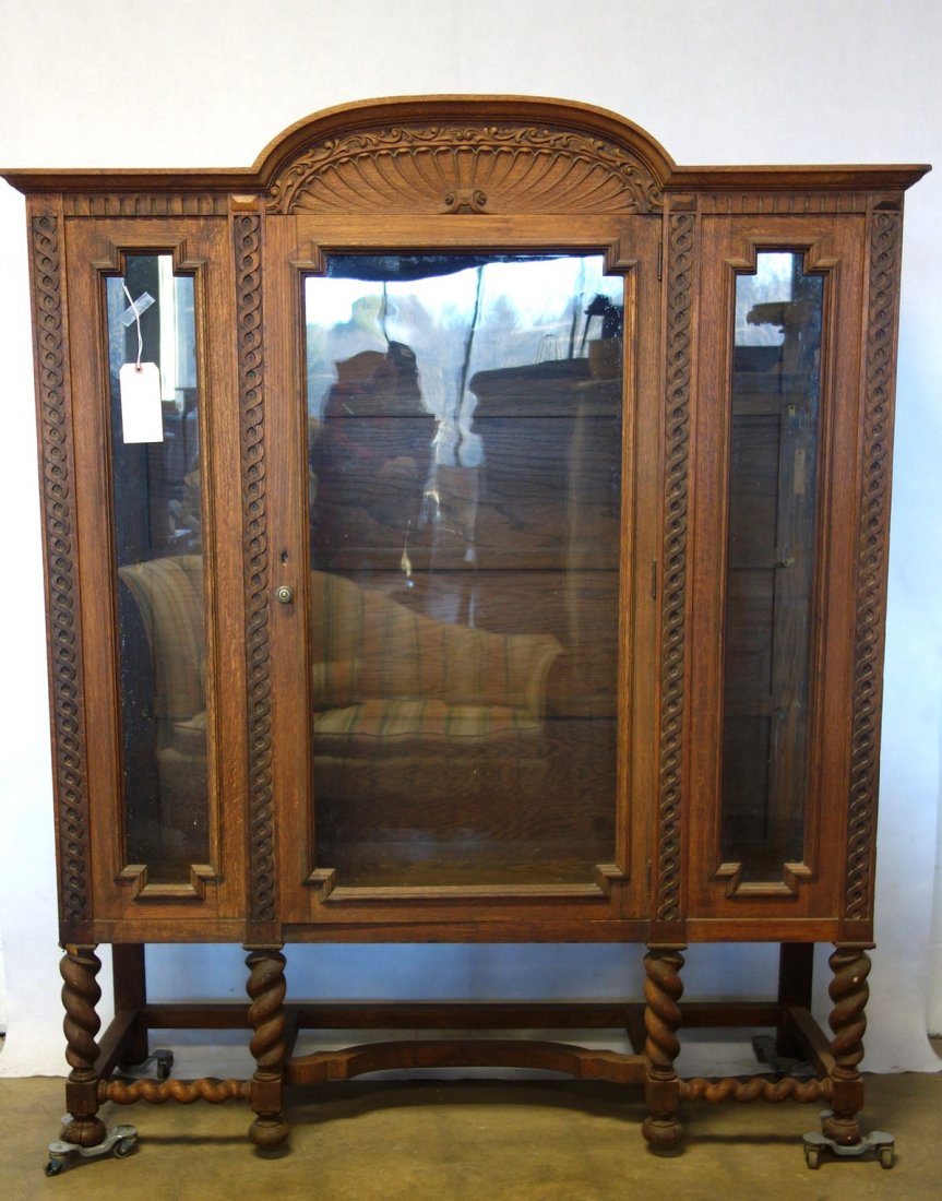 Oak single door glass china cabinet with a shell carved: Oak single door glass china cabinet with a shell carved crest and barley turned legs. Circa 1900. 66"H x 55 1/4"W x 17 1/4"D. Good condition.