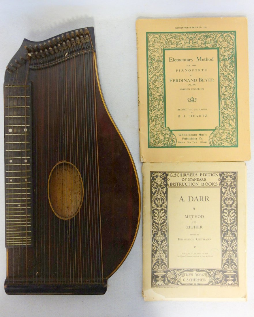 Zither with two instruction booklets circa 1900. Two: Zither with two instruction booklets circa 1900. Two slight shrinkage cracks to the body otherwise good condition.