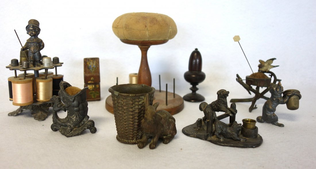 Collection of mostly figural sewing items including: A: Collection of mostly figural sewing items including: A metal figural thread and thimble holder with a cat and a dog jumping over a fence signed "A. Frankfield & Co."; a metal pin cushion in the form o