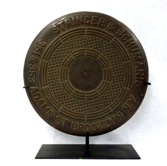 Cast iron coal chute cover with address marked: Cast iron coal chute cover with address marked "STRINGER & SCHUMANN 351 & 353 ADAMS ST. BROOKLYN NY" - 18"D. Very good original condition. Displayed on a museum iron mount. Provenance: From the Sandra