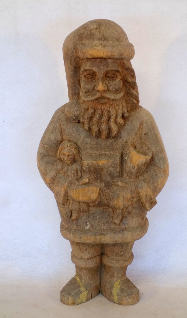 Carved wooden Santa Claus holding toys sculpture with: Carved wooden Santa Claus holding toys sculpture with natural finish. Probably mid 20th century 18.25"H. Slight surface wear, otherwise very good condition.