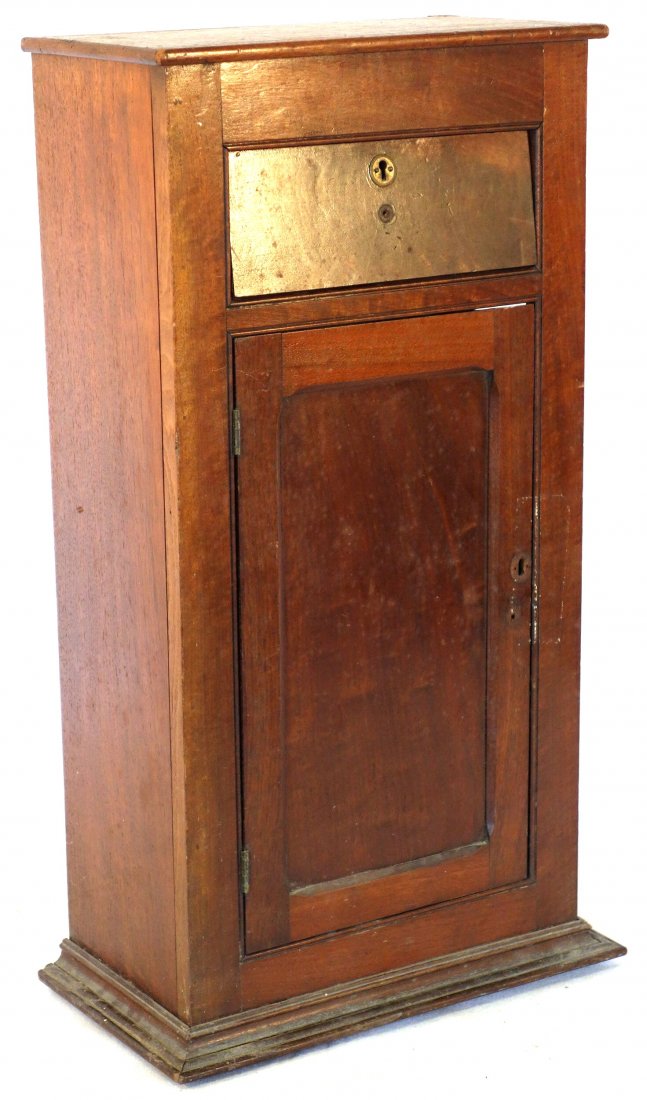Small wall mounted black walnut country storage cabinet: Small wall mounted black walnut country storage cabinet having 1 drawer over 1 door with cubby hole interior. Late 19th century. Good condition. 29"H x 15"W x 9"D.