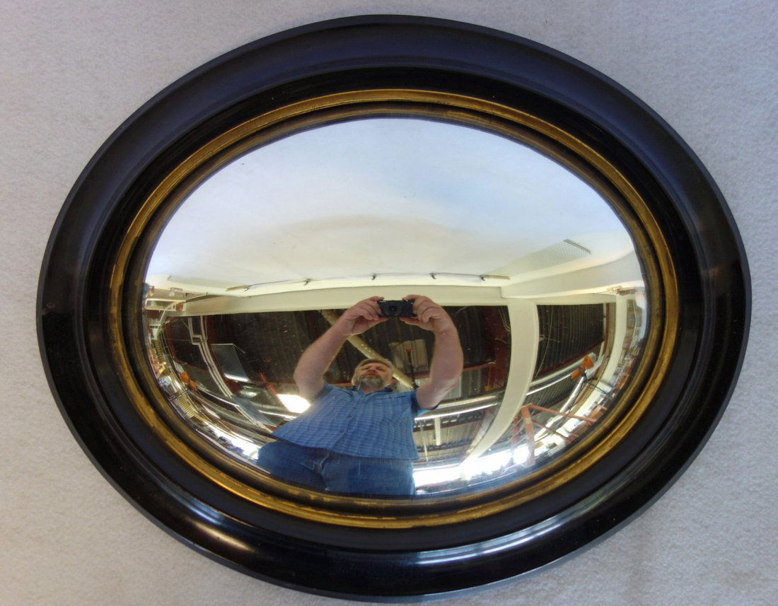 Convex oval wall mirror with mahogany or walnut frame: Convex oval wall mirror with mahogany or walnut frame having a gold inset. Circa 1850. Replaced backboard, otherwise very good condition. 18.25" x 15" overall size.