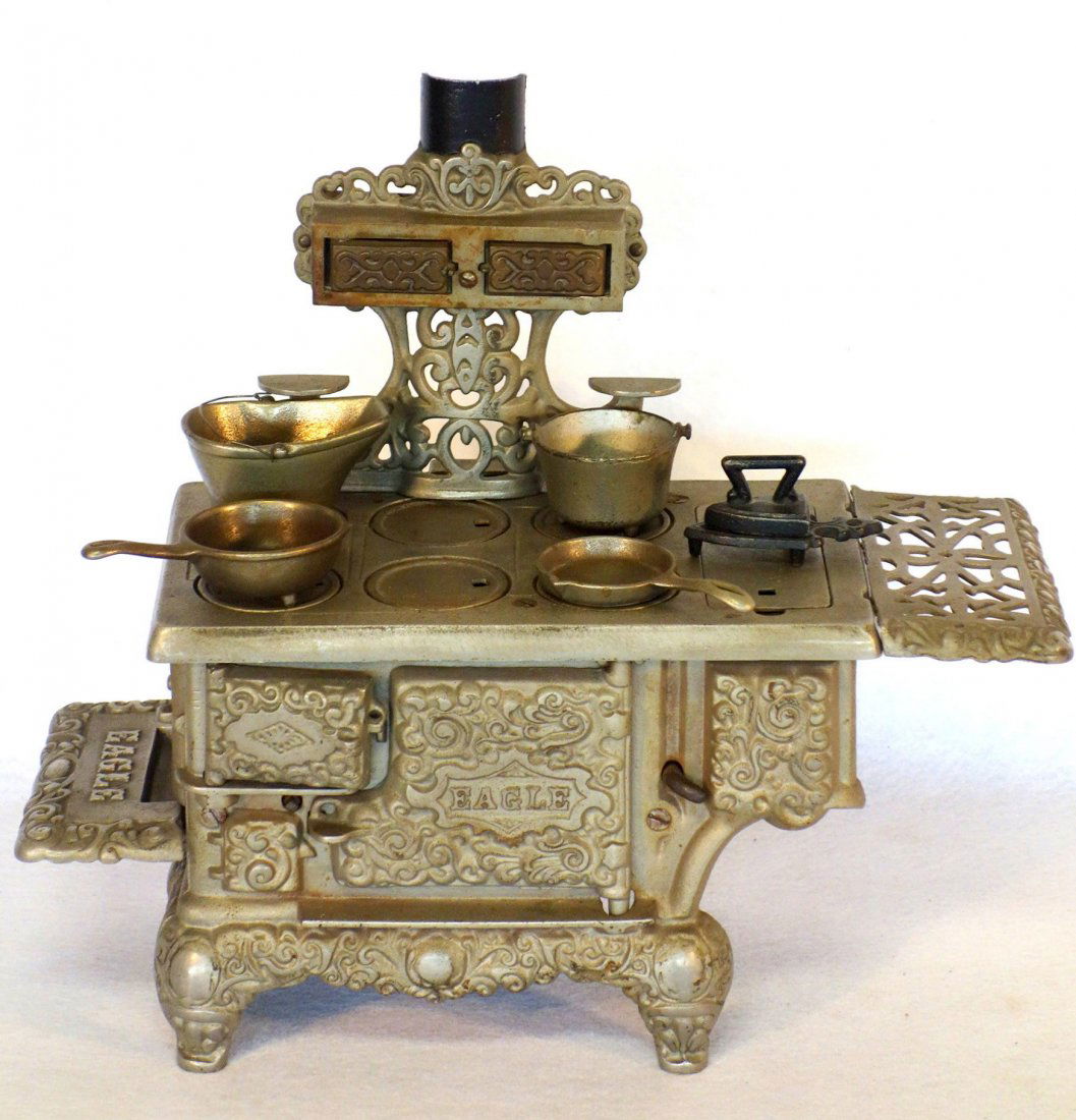 Large ornate nickel plated doll stove signed Eagle -: Large ornate nickel plated doll stove signed Eagle - complete with 4 cast iron cooking pots and a miniature iron & trivet. 14"H x 16"L. Excellent condition.
