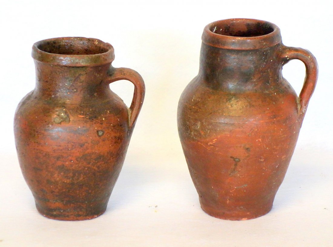 Two primitive redware jars with handle - unknown: Two primitive redware jars with handle - unknown origin, probably 19th century or earlier - each 8"H. Several chips on rim, otherwise good condition.