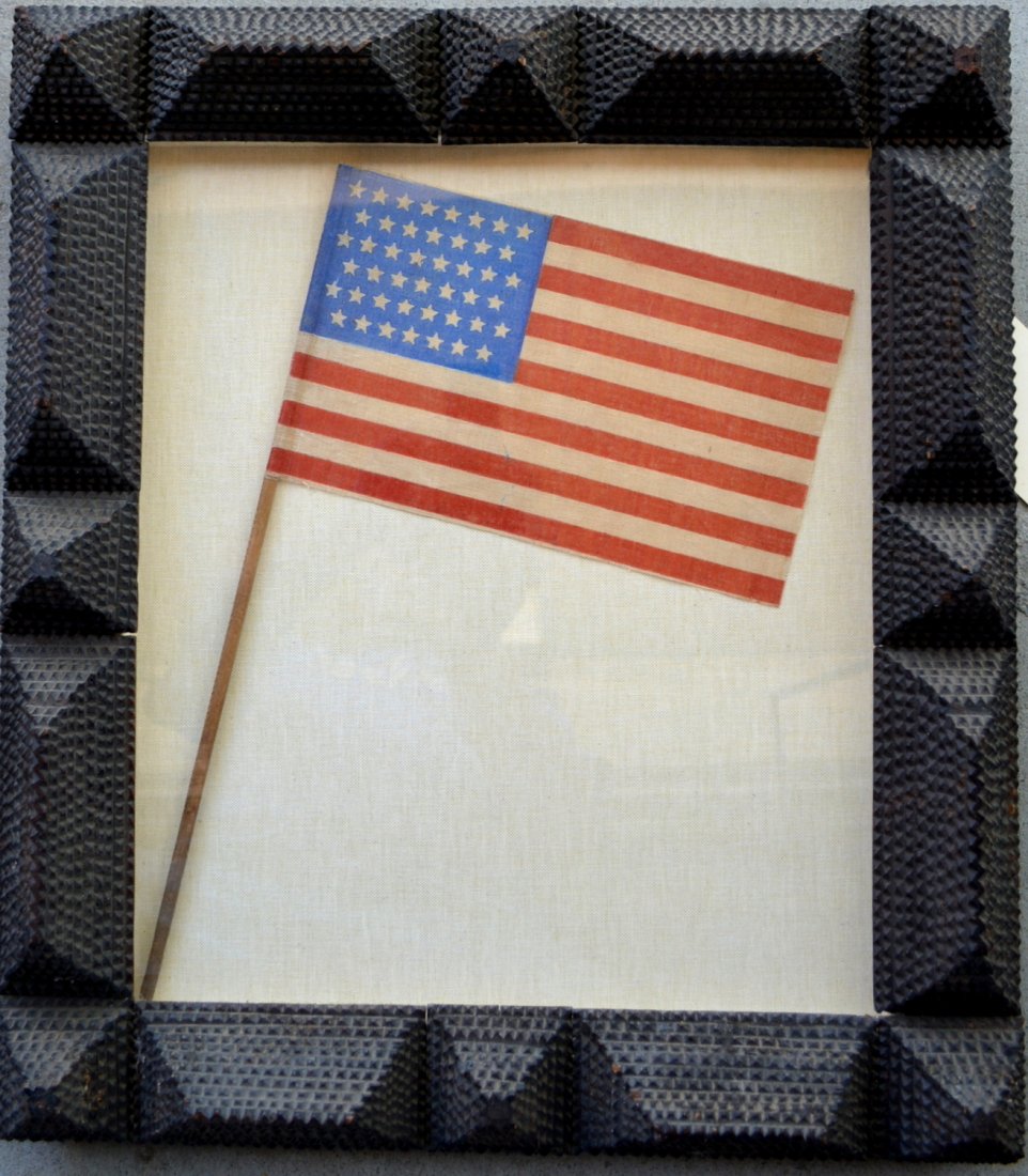 Tramp art late 19th century frame, currently holding a: Tramp art late 19th century frame, currently holding a 45 star printed American flag - the tips of 6 of the pyramids are missing but hardly noticeable otherwise very good condition - opening size 16.7