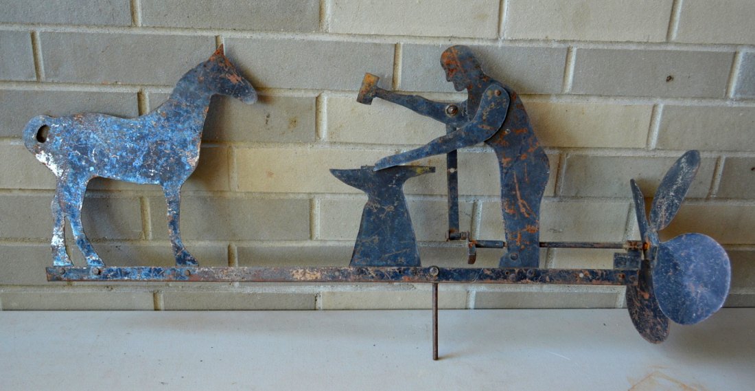 Tin blacksmith and horse whirligig, mid 20th century.: Tin blacksmith and horse whirligig, mid 20th century. Original black paint with wear and minor surface rust, in good working order - 31"L.