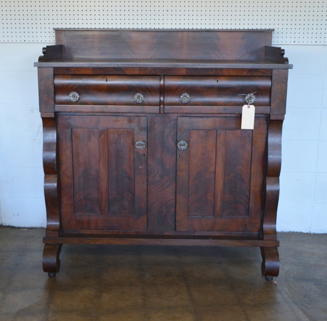 Empire mahogany sideboard with gallery top and having 2: Empire mahogany sideboard with gallery top and having 2 drawers over 2 doors with scrolled columns and feet - 2 glass pulls with chips otherwise very good condition. Mid 19th century. 50.5"W x 23.5"D 