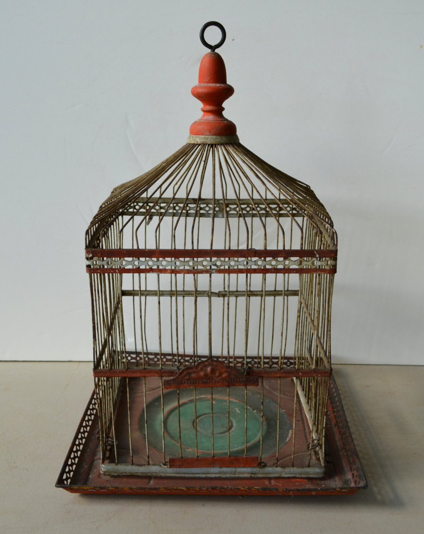 Tole birdcage in original red and white paint with: Tole birdcage in original red and white paint with turned wooden finial, late 19th century - approximately 16.5"H. Two of the 4 clamps that hold the cage to the base are missing, else good condition.