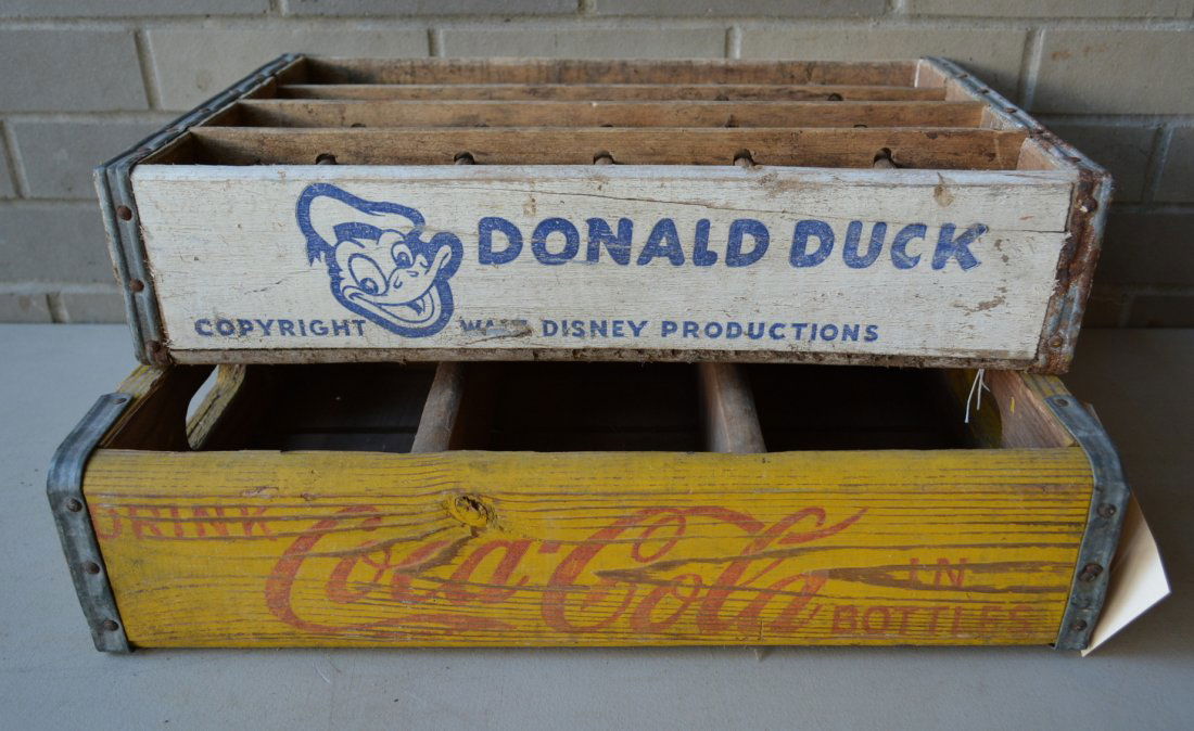 Two advertising wooden soda bottle holders including: Two advertising wooden soda bottle holders including Donald Duck in blue and white and Coca Cola in red and yellow. Both original paint in good condition. Circa 1950's.