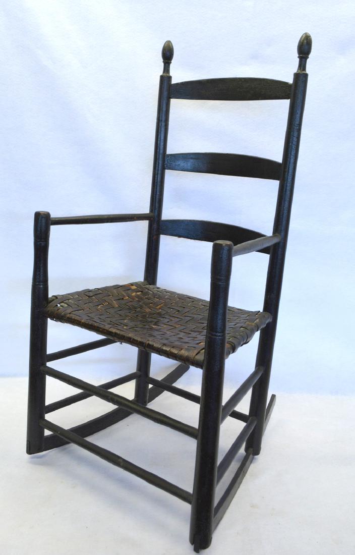 Ladder back rocker with arms with woven cane seat in: Ladder back rocker with arms with woven cane seat in black paint. Good condition. Late 18th century. Provenance: From a local historic Bedford village home, owners downsizing collection.