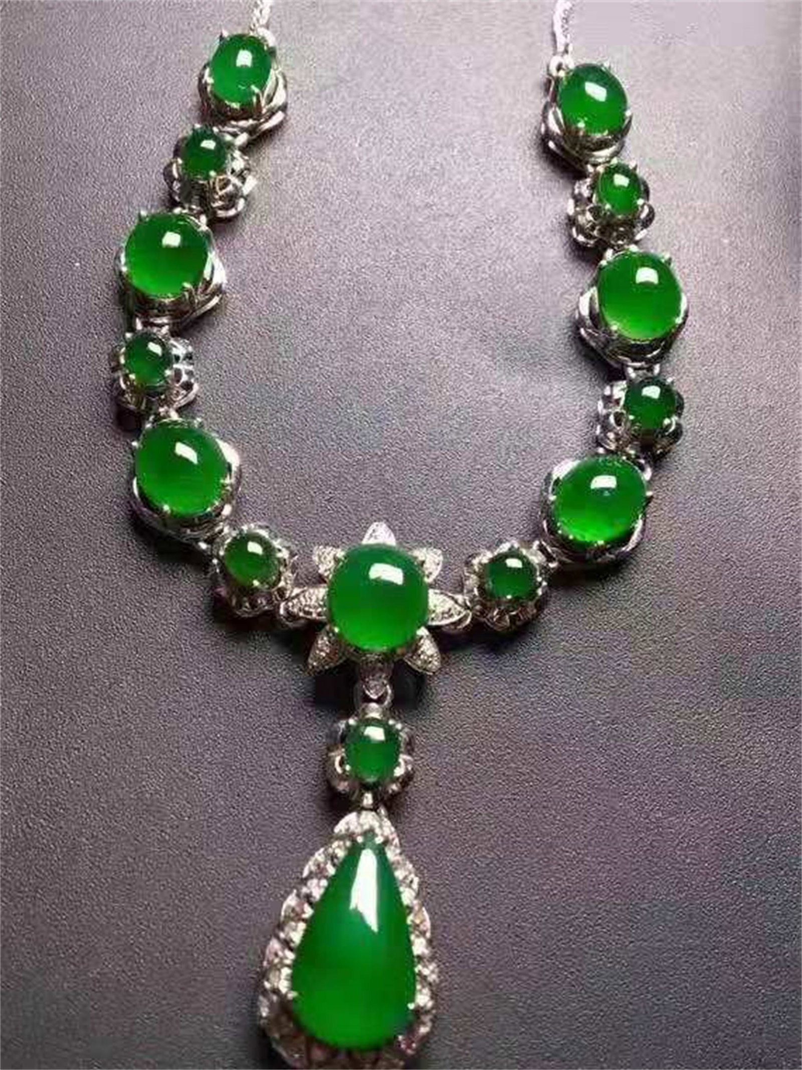 A CHINESE 18 KARAT GOLD NATURAL GREEN JADEITE NECKLACE: Bare stone Lg. 11.9mm, Wd. 7.9m Different sizes