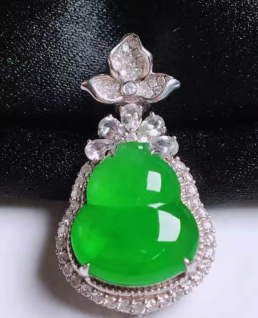 A Carved Jadeite Pendant of Double Gourd Shape: A Carved Jadeite Pendant of Double Gourd Shape . Ht. 26.mm Wd. 13mm