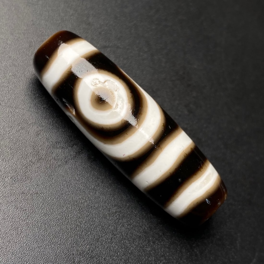 A Chinese Carved Agate DZI Bead: A Chinese Carved Agate DZI Bead. Lg. 3.9cm, Diam. 1.25cm, Wt. 10g