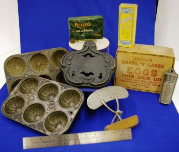 A Tray Of Early Kitchen Ware: Two Muffin Tins, A Chopper, A Trivet, A Tin, A Grater, A Crimper, And An Egg Box