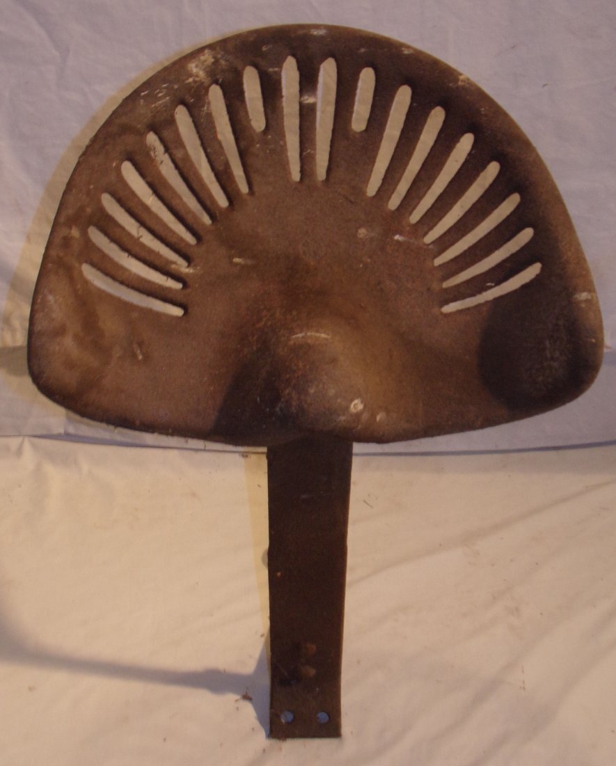Cast Iron Tractor/Farm Implement Seat: Cast iron tractor/farm implement seat on iron mount, unmarked, rust visible, 17 ½” W x 14” D x mount approximately 20” T