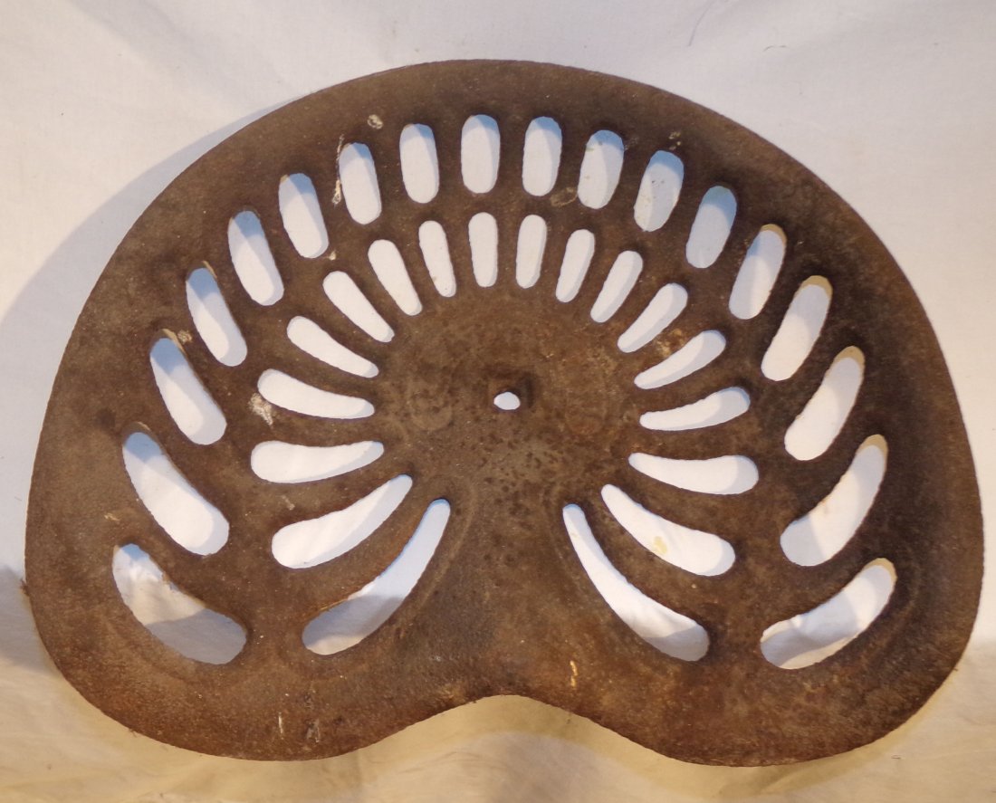 Cast Iron Tractor/Farm Implement Seat: Cast iron tractor/farm implement seat, name on center of seat (illegible), rust visible, 19” W x 16” D