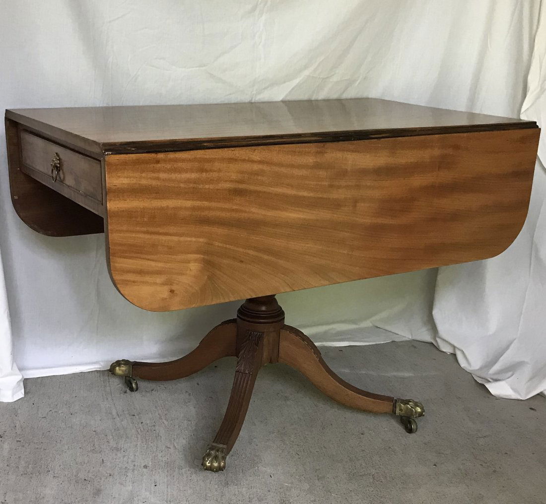 19th C Duncan Phyfe Breakfast Table: 19th century Duncan Phyfe cherry drop leaf breakfast table having 1 drawer & 1 fake drawer w/brass lion heads ring pulls, drop leaves have rounded corners, table mounted o turned urn form table base,