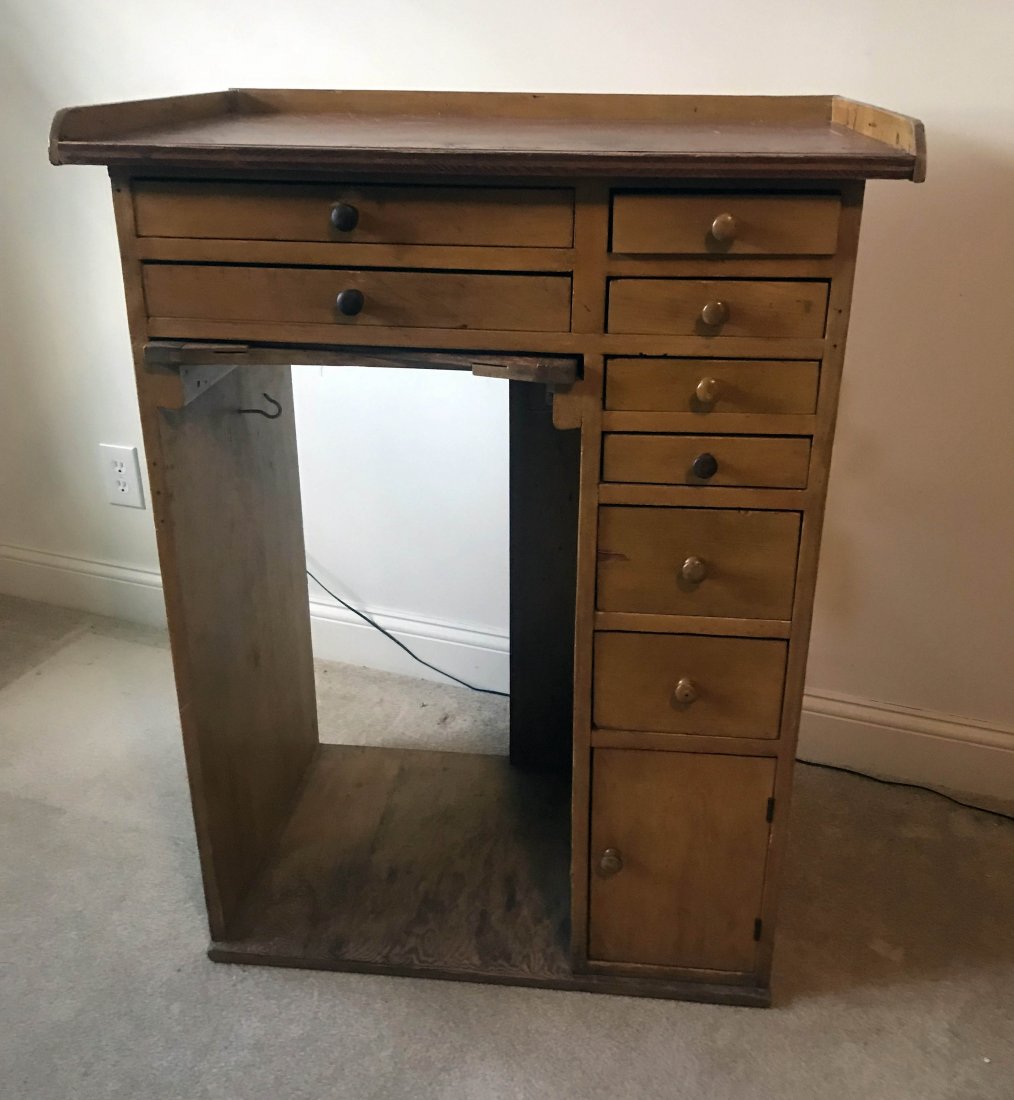 FURNITURE, ACCESSORIES, COUNTRY COLLECTIBLES, TOYS,: Primitive jeweler’s/watchmaker’s bench, the top over 8 drawers of various lengths with wooden knob pulls and 1 small blind door at base, sliding shelf at kneehole, on a plywood base, yellowish pai