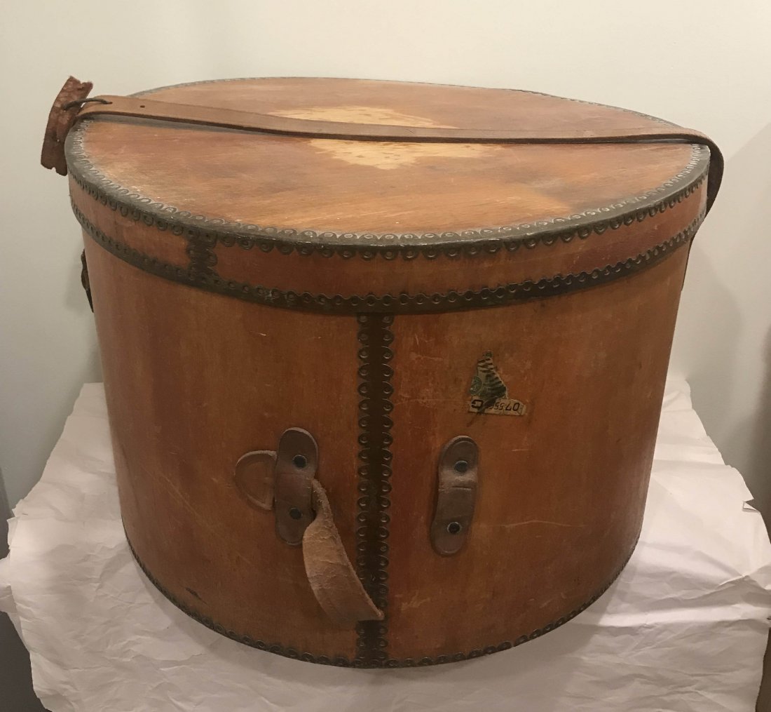 FURNITURE, ACCESSORIES, COUNTRY COLLECTIBLES, TOYS,: Vintage round wooden hat box with decorated metal mounts, leather handle and strap are both damaged, old wear, scratches and scuffing visible, 11 ¾” T x 17 5/8” D