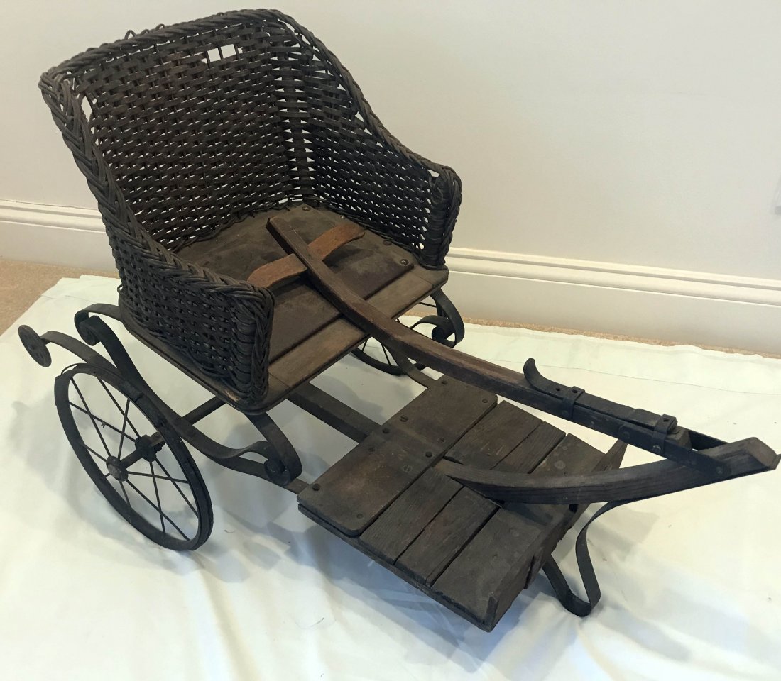 FURNITURE, ACCESSORIES, COUNTRY COLLECTIBLES, TOYS,: Child's 2 wheel pull cart w/wicker seat, wooden frame w/iron springs, wooden foot rest and wood "T" pull handle, metal spoke wheels, wicker seat shows some damage, 20 1/2" T x 18 1/2" W x 35" L (handl