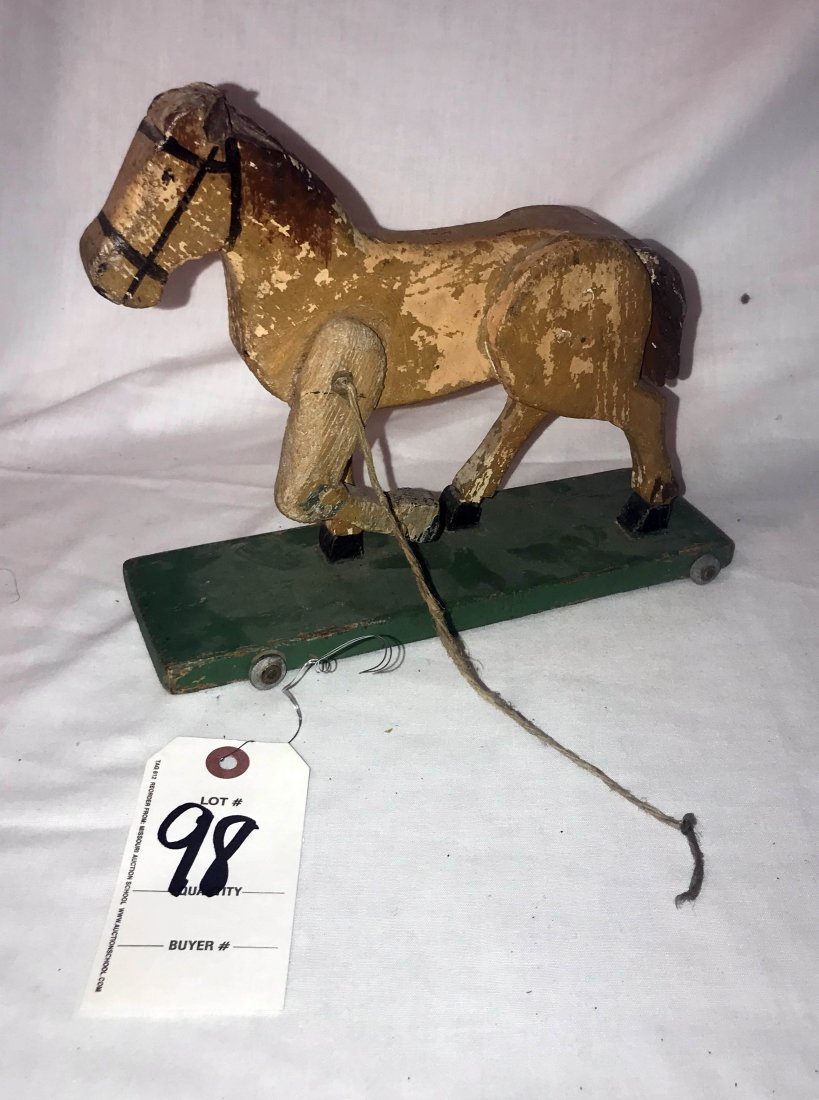 FURNITURE, ACCESSORIES, COUNTRY COLLECTIBLES, TOYS,: Primitive wooden folk art horse pull toy mustard brown paint w/brown mane and tail; 1 leather ear partially missing, on a base painted green w/4 small galvanized metal wheels; original unrestored cond