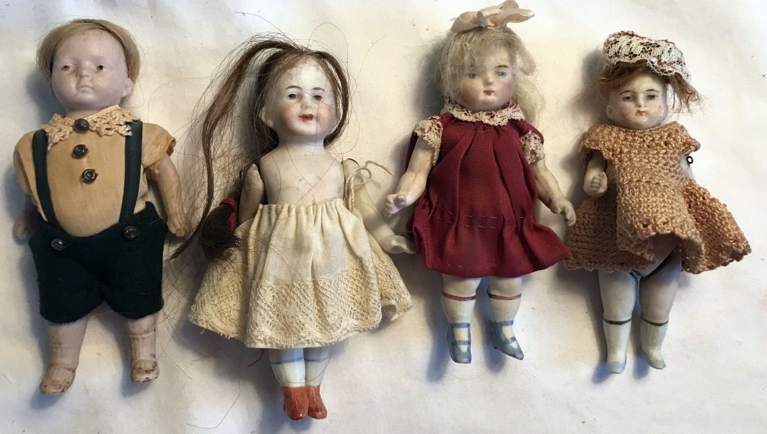 DOLLHOUSE, DOLLS, MINIATURES: Group of 4 miniature bisque dolls, all with movable arms and handpainted features: boy wearing black shorts with yellow linen shirt, showing signs of deterioration, movable legs, wig attached, marked 