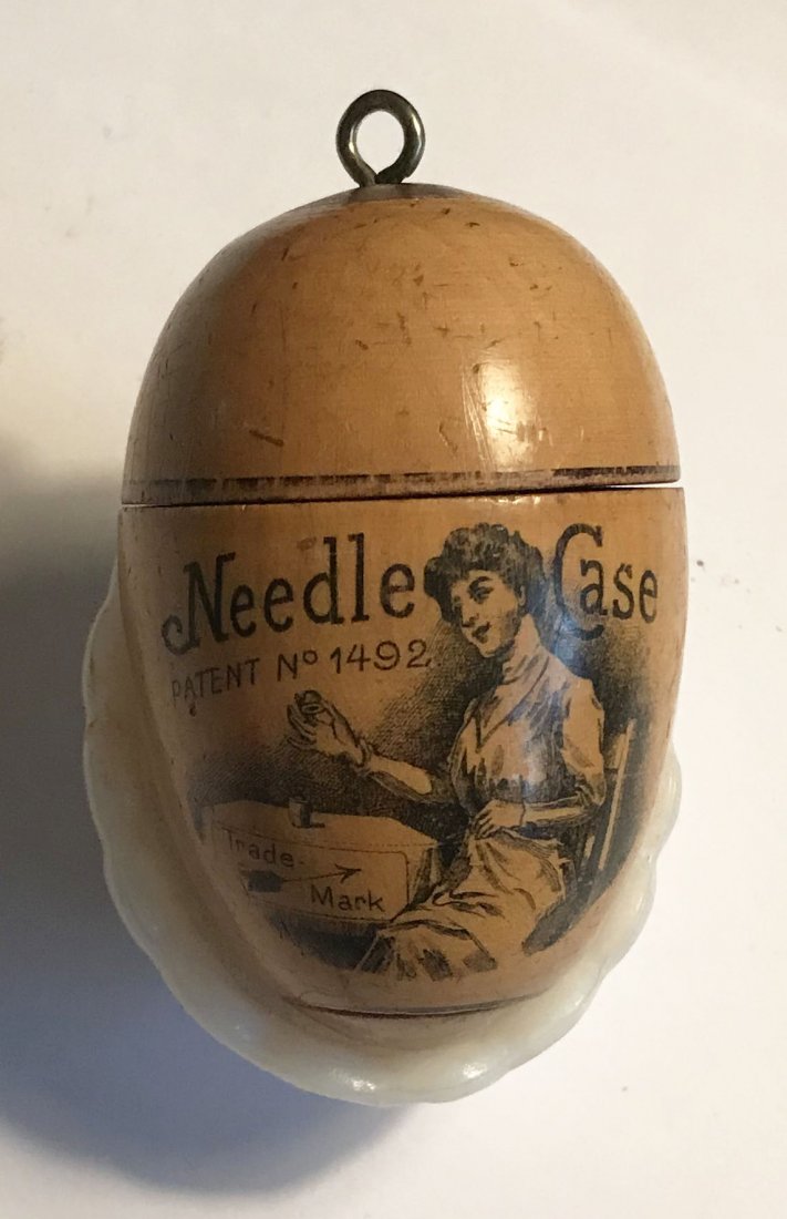 FURNITURE, ACCESSORIES, COUNTRY COLLECTIBLES, TOYS, ETC: Wooden egg shaped needle case, marked The Columbian Egg Needle Case patent no. 1492, trademark, lithograph of lady holding a needle case removing needles; movable interior holds needles, different siz