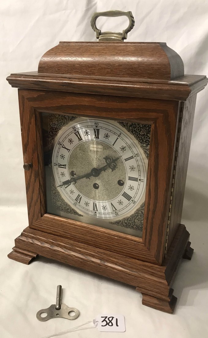 HANDCRAFTED JEWELRY, STERLING AND PLATED SILVER, CLOCKS: Hamilton reproduction bracket clock, Wheatland Model, in oak case w/brass handle brass movement marked B, 2 jewels #340-020, Western Germany w/key, dial w/Roman Numerals, floral and leaf decorated cor
