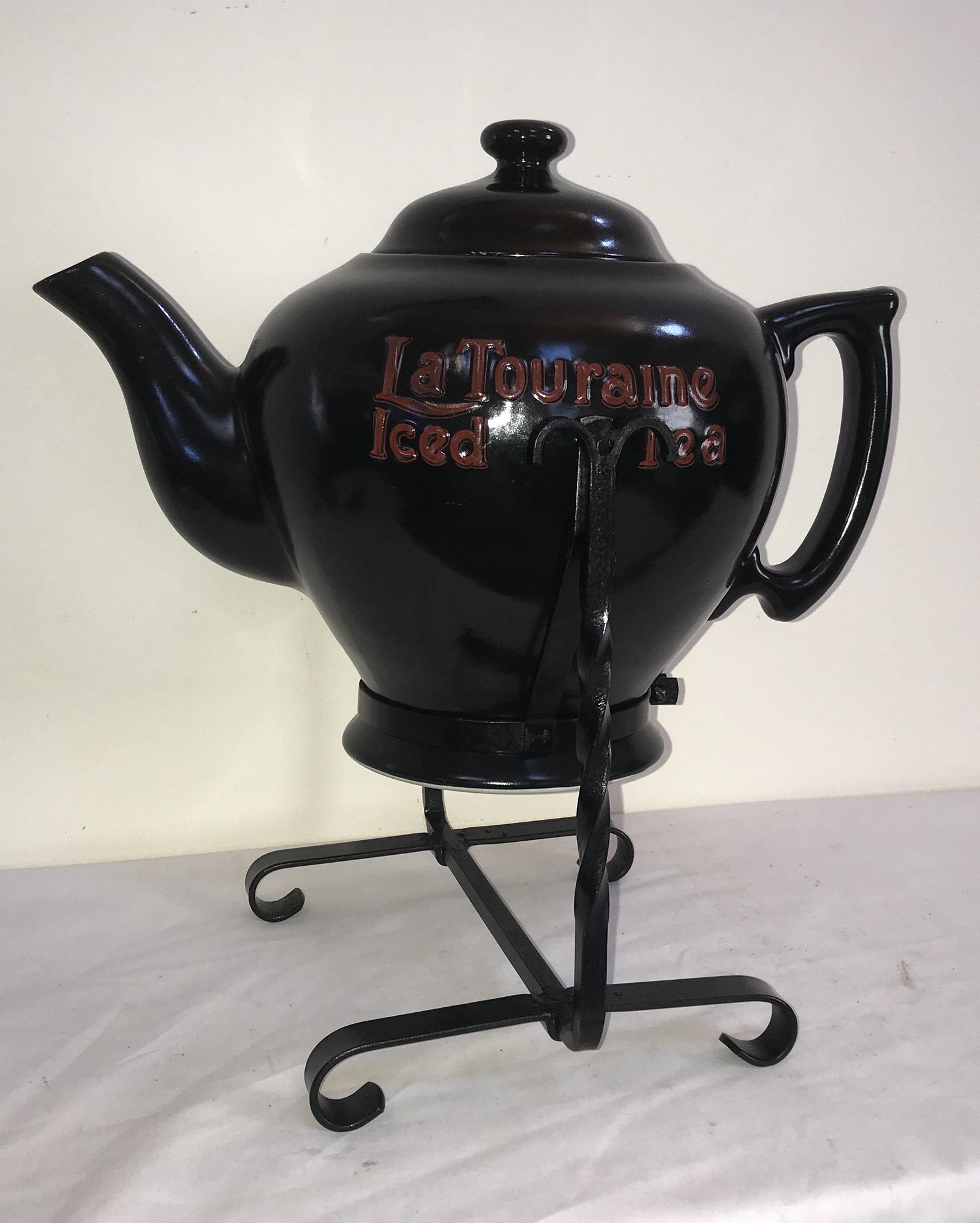 La Touraine Iced Tea Pottery Kettle: Pottery kettle w/lid handle and spout advertising La Touraine Iced Tea w/black glaze and red lettering, kettle marked Scammell China, Trenton, NJ together w/wrought steel footed pouring stand, overall