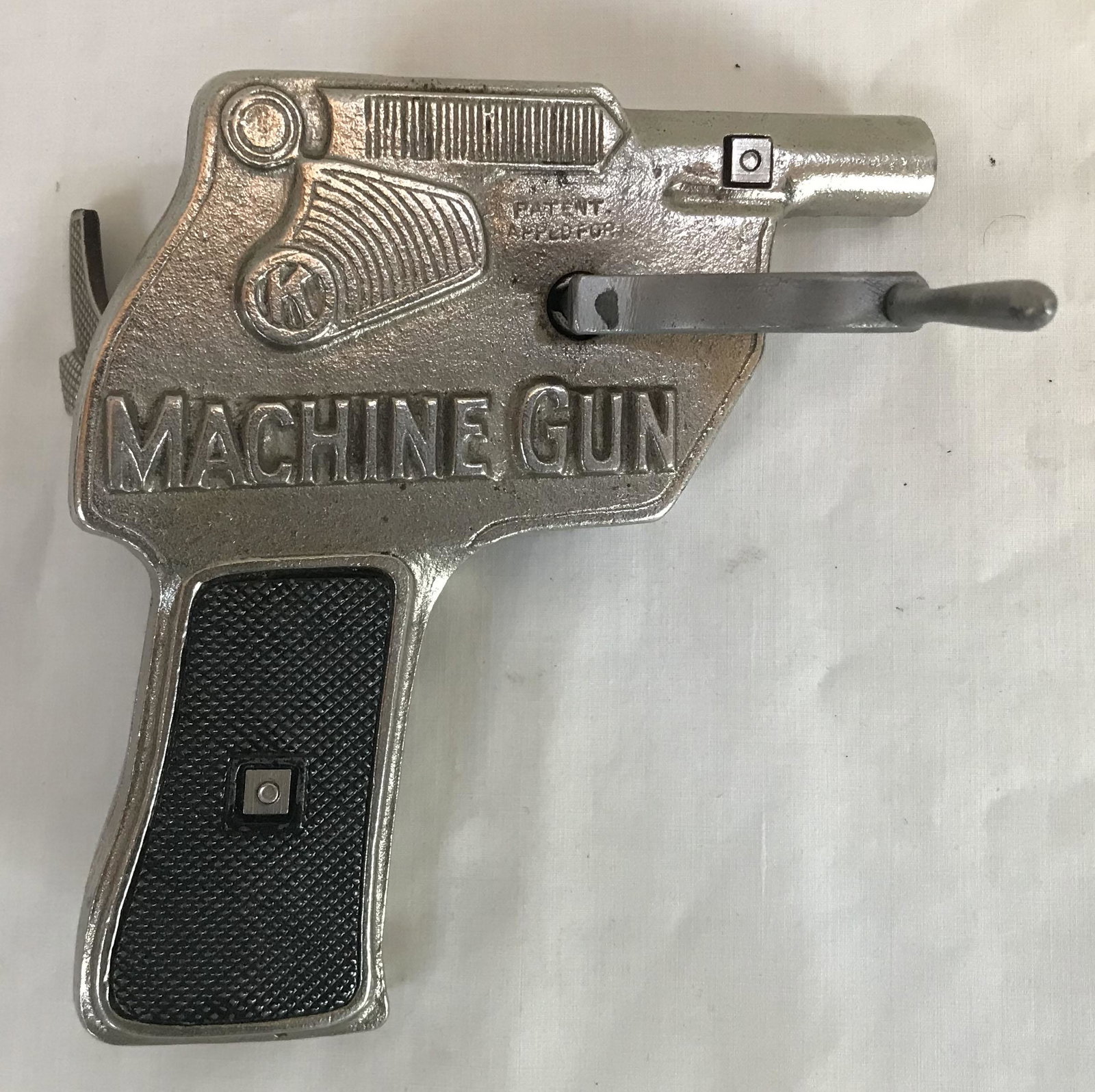 Die Cast Machine Gun Toy Cap Gun: Die cast metal machine gun, RA-TA-TA-TAT, toy cap gun, silver finish, minor surface rust and wear visible together w/crank; 5 1/8" T x 5" W x 5/8" D