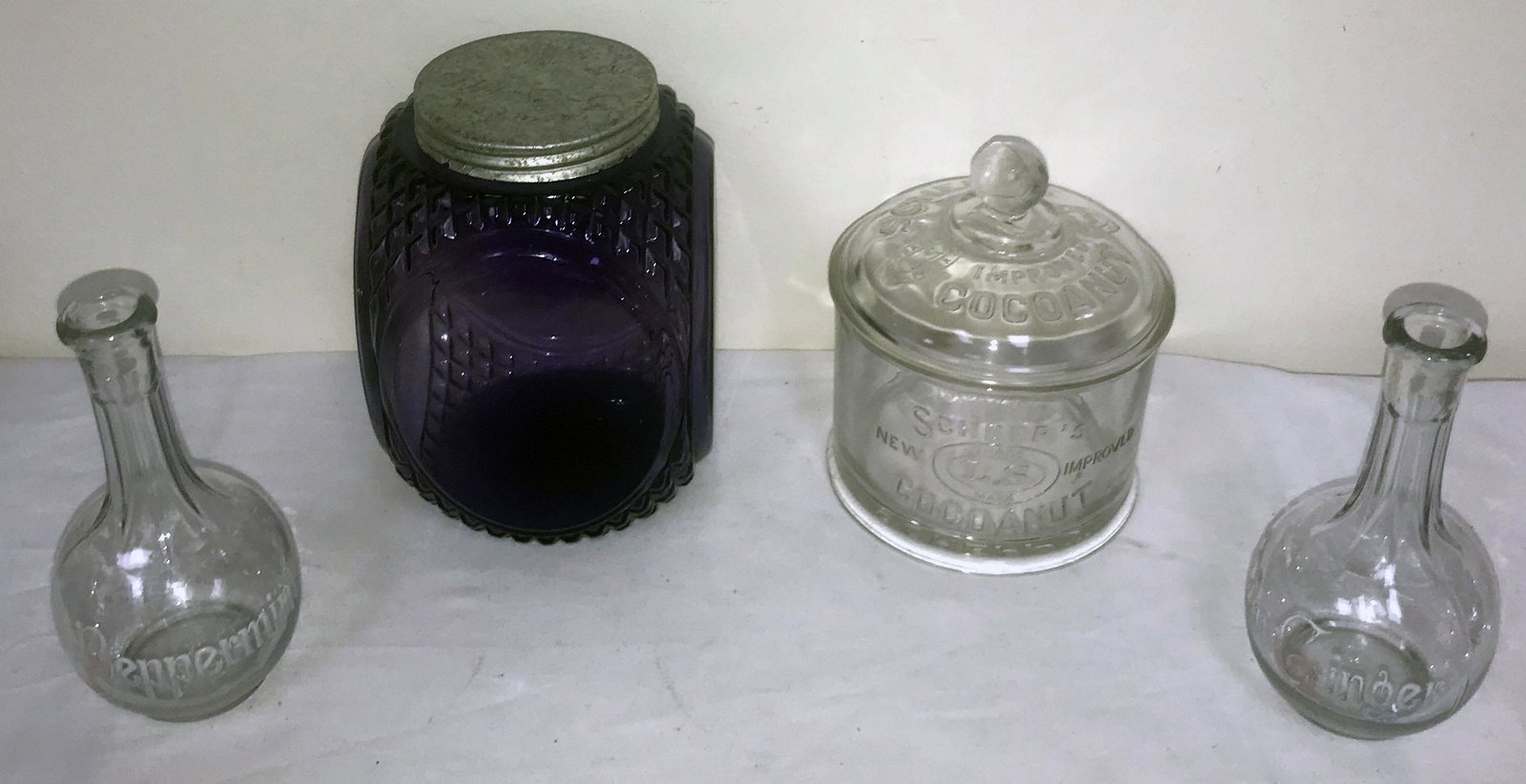 Grouping of Candy Store/Ice Cream Parlor Collectibles: Grouping of candy store/ice cream parlor collectibles: purple/amethyst biscuit/cracker jar w/oval panels, aluminum threaded lid showing wear and corrosion 7 3/4" T x 5 1/2" square; clear Schepp's New 